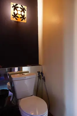 a bathroom with a toilet with a light on the wall at Bangkok Tree House Bang Kachao in Bangkok