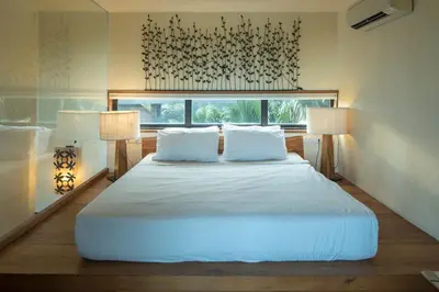 a bedroom with a large white bed with two lamps at Bangkok Tree House Bang Kachao in Bangkok