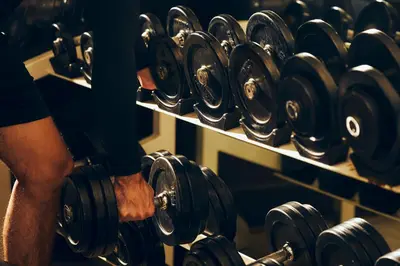 a man is holding dumbbells in a gym at The Davis Bangkok in Bangkok
