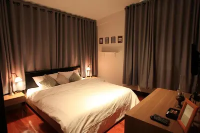 a bedroom with a white bed and a table at House 23 Guesthouse in Bangkok