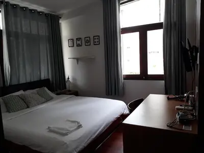 a bedroom with a bed and a desk and a window at House 23 Guesthouse in Bangkok