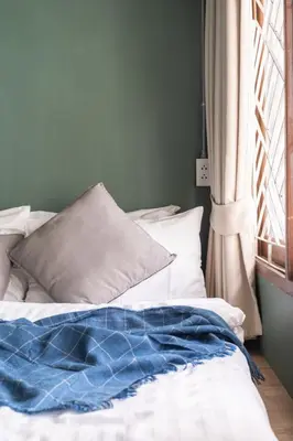 a bed with a blue blanket on it next to a window at Better Moon Guesthouse in Bangkok