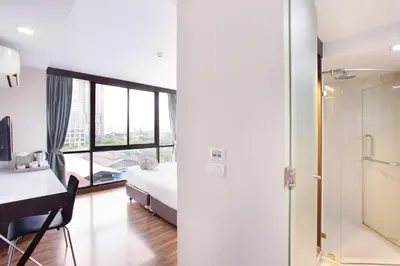 a bedroom with a bed and a desk and a window at Mida Hotel Ngamwongwan - SHA Plus in Nonthaburi