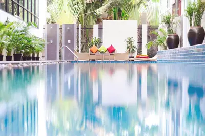 a swimming pool with chairs and plants in a building at Mida Hotel Ngamwongwan - SHA Plus in Nonthaburi