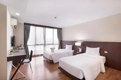 a hotel room with two beds and a desk at Mida Hotel Ngamwongwan - SHA Plus in Nonthaburi
