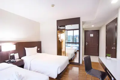 a hotel room with two beds and a desk at Mida Hotel Ngamwongwan - SHA Plus in Nonthaburi