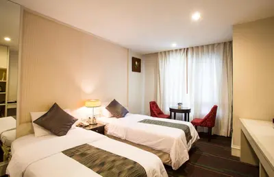 a hotel room with two beds and a window at Aphrodite Inn Bangkok in Bangkok
