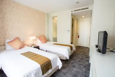 a hotel room with two beds and a flat screen tv at Aphrodite Inn Bangkok in Bangkok