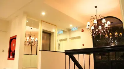 a chandelier in a living room with a staircase at Aphrodite Inn Bangkok in Bangkok