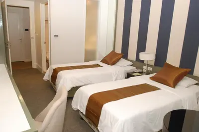 a hotel room with two beds and a mirror at Aphrodite Inn Bangkok in Bangkok