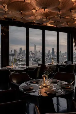 a restaurant with tables and chairs and a view of the city at Siam At Siam Design Hotel Bangkok in Bangkok