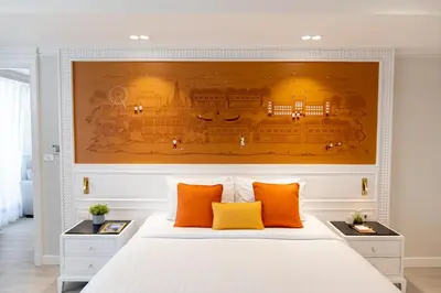 a large painting above a bed with orange pillows at Centre Point Plus Hotel Silom - Newly Renovated in Bangkok