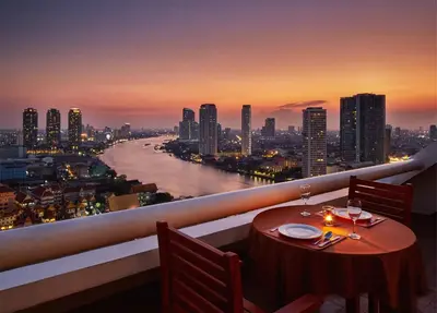 a table on a balcony with a view of a river at Centre Point Plus Hotel Silom - Newly Renovated in Bangkok
