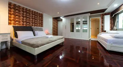 a bedroom with two beds and a wooden wall at Clean Comfy Cozy easy to go Siam Paragon and Chatuchak Market in Bangkok