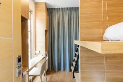 a small bedroom with a bed and a window at Atnest Hostel in Bangkok
