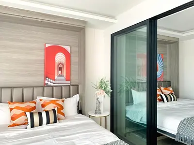 a bedroom with two beds with orange and white pillows at Sukhumvit Asok Modern Suite in Bangkok