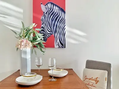 a table with two glasses and a painting of a zebra at Sukhumvit Asok Modern Suite in Bangkok