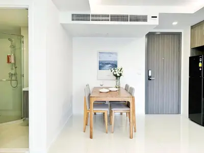 a dining room with a wooden table and chairs at Sukhumvit Asok Modern Suite in Bangkok