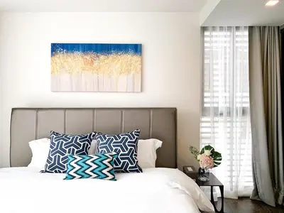 a bedroom with a bed with blue and white pillows at Sukhumvit Asok Modern Suite in Bangkok