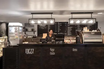 a woman standing behind the counter of a coffee shop at Centara Life Government Complex Hotel & Convention Centre Chaeng Watthana in Bangkok