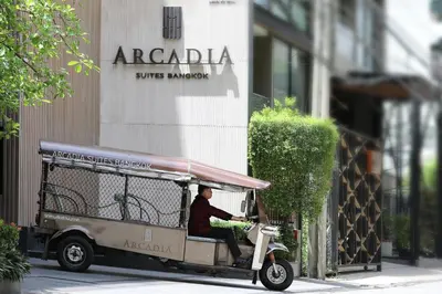 a man riding a golf cart on a street at Arcadia Suites Ploenchit Bangkok in Bangkok