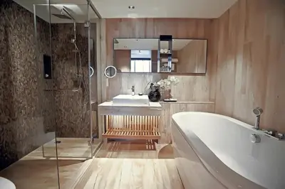 a bathroom with a tub and a sink and a mirror at Arcadia Suites Ploenchit Bangkok in Bangkok