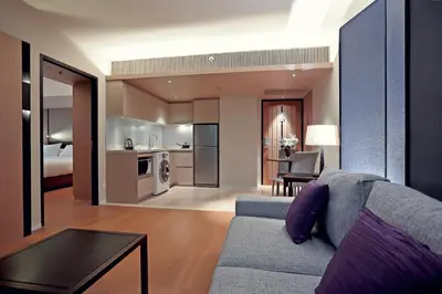 a living room with a couch and a kitchen at Arcadia Suites Ploenchit Bangkok in Bangkok