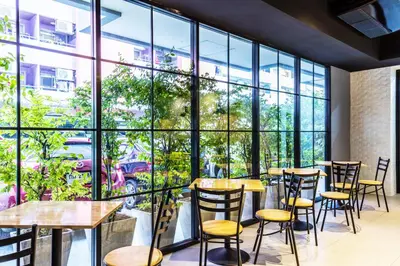 a restaurant with tables and chairs and large windows at Aliz Hotel in Nonthaburi