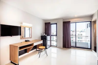 a room with a desk and a television and windows at Aliz Hotel in Nonthaburi