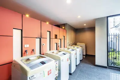a row of washing machines are lined up in a room at Aliz Hotel in Nonthaburi