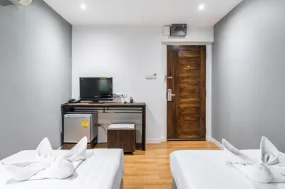 two beds in a room with a tv on a table at The Richy Place Guest House in Bangkok