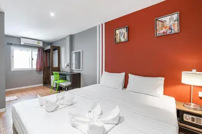 a bedroom with a large bed with white sheets at The Richy Place Guest House in Bangkok