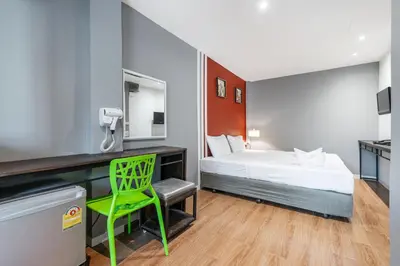 a room with a bed and a desk with a green chair at The Richy Place Guest House in Bangkok