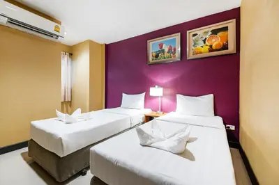 a room with two beds and a purple wall at The Richy Place Guest House in Bangkok