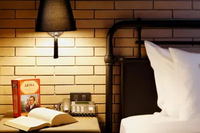 a bed with a lamp and a book and a telephone at Baan Chart in Bangkok