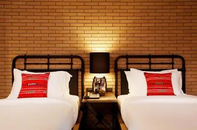 two beds with red pillows next to a brick wall at Baan Chart in Bangkok