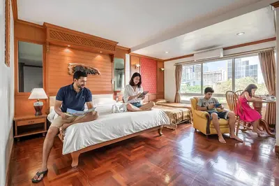 a group of people sitting around a bed in a room at Royal Ivory Sukhumvit Nana in Bangkok