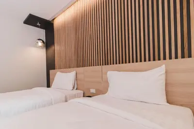 two beds in a hotel room with white pillows at So good Hotel Bangkok in Bangkok