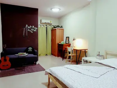 a bedroom with a bed and a chair and a guitar at NBH.@ Prannok in Bangkok