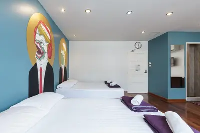 two beds in a room with a painting on the wall at 99 Hostel Khaosan in Bangkok