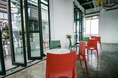a room with a table and chairs and windows at Fine Bed Hotel in Nonthaburi