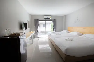 a bedroom with two beds and a desk and a window at Fine Bed Hotel in Nonthaburi