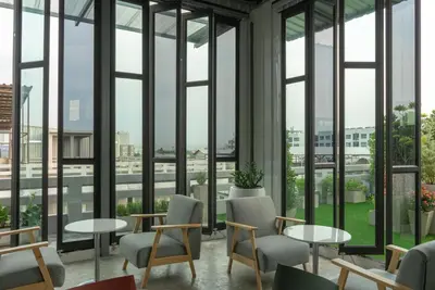 a room with tables and chairs and large windows at Fine Bed Hotel in Nonthaburi