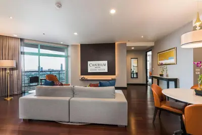 a living room with a couch and a table at Chatrium Hotel Riverside Bangkok in Bangkok