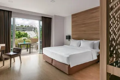 a hotel room with a bed and a balcony at Adelphi Grande Sukhumvit in Bangkok