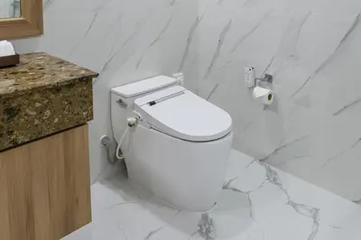 a white toilet in a bathroom with marble walls at Adelphi Grande Sukhumvit in Bangkok