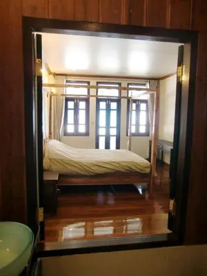 a bedroom with a bed in a room with windows at The Royal ThaTien Village in Bangkok