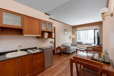 a kitchen and living room with a sink and a table at Grand Diamond Suites Hotel in Bangkok