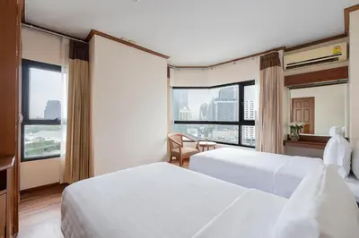 a hotel room with two beds and a large window at Grand Diamond Suites Hotel in Bangkok