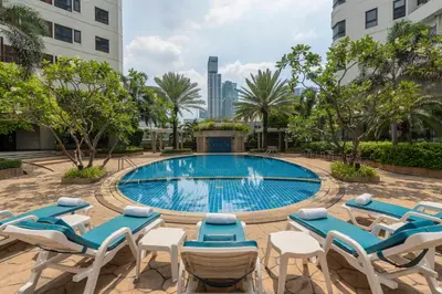 a pool with chaise lounge chairs and a group ofvisorvisorvisorvisorvisor at Grand Diamond Suites Hotel in Bangkok